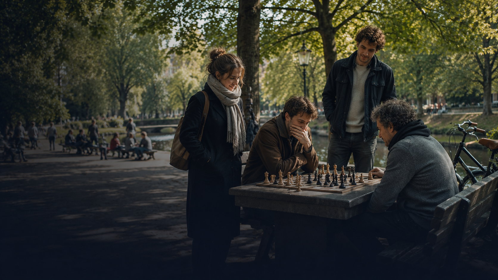 A group playing chess at a stone table in an Amsterdam park by the canal